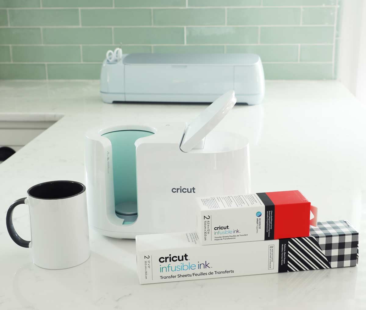 Cricut Mug Press Machine on a counter with infusible ink and the cricut maker 3.