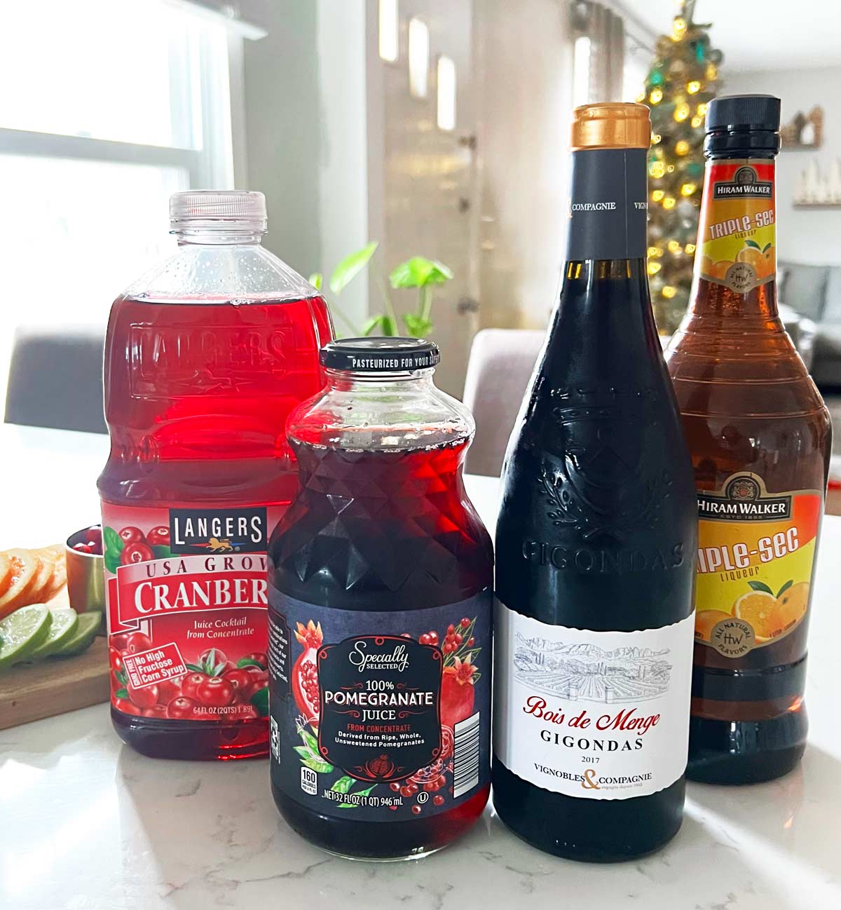 Christmas Sangria Ingredients on a kitchen counter cranberry juice, pomegranate juice, red wine and triple sec.