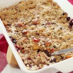Fresh baked Fruit Crisp with peaches in a white baking dish on top of the kitchen counter.