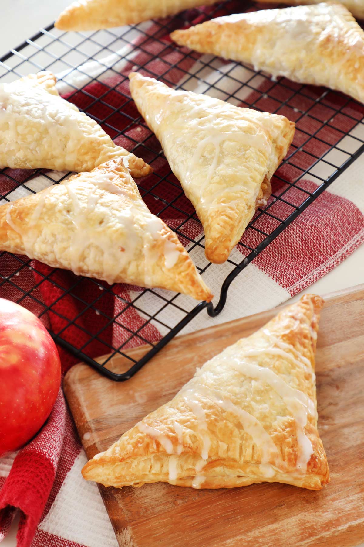 Apple turnovers on a backing rack and cutting board. 