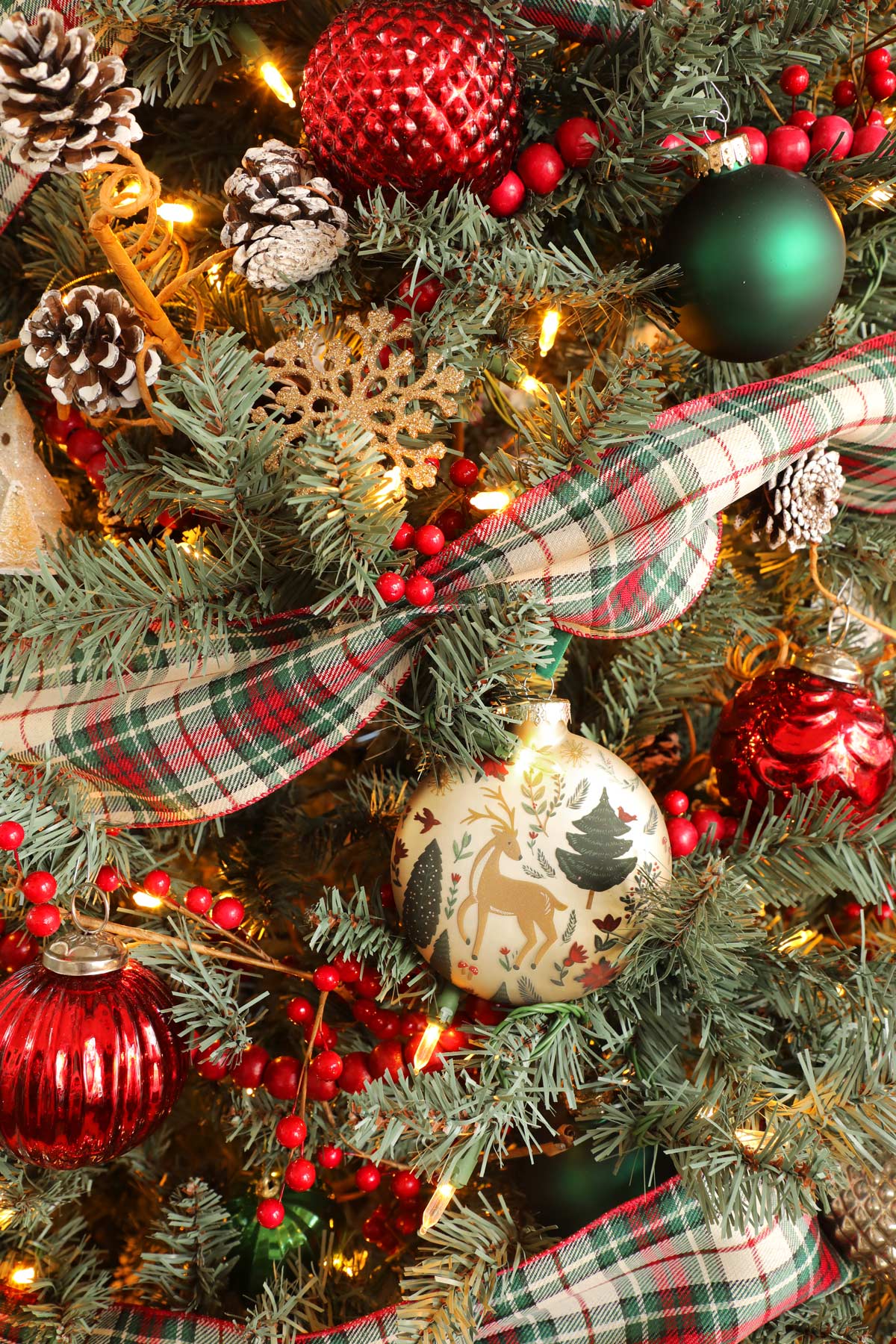 A close up of a Christmas tree with plaid ribbon and intricate ornaments.