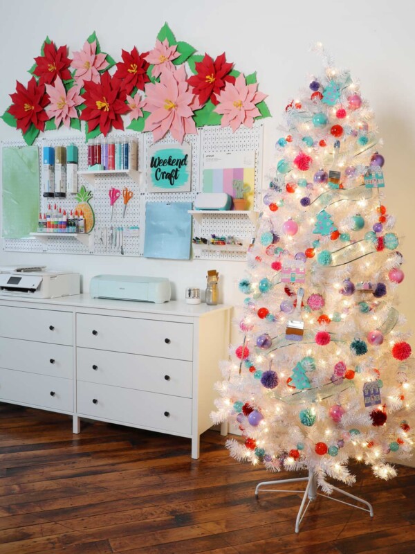 A beautiful white christmas tree with colorful ornaments in a craft room.