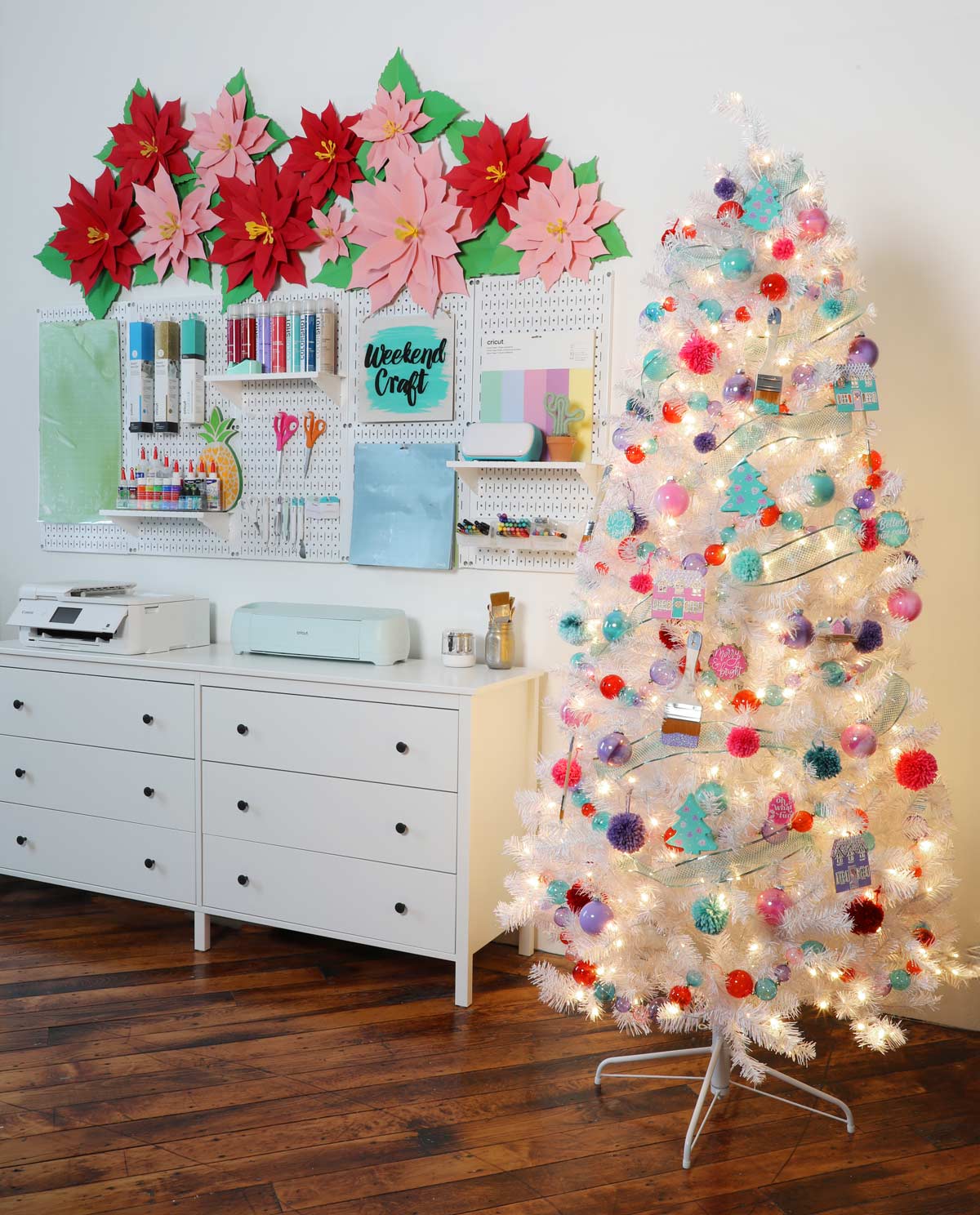 A beautiful white christmas tree with colorful ornaments in a craft room. 