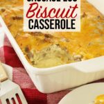 Sausage egg biscuit casserole in white casserole dish with spatula off to the side on top of kitchen counter.