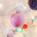 A pink painted marbled ornament on a white Christmas tree.