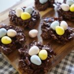 Birds nest cookies are arranged on top of a wooden board on the kitchen counter.