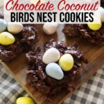 Chocolate coconut birds nest cookies are arranged on top of a wooden board.