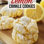 A stack of 3 lemon crinkle cookies are on a wooden board with more lemon crinkle cookies and a cut lemon in the background.