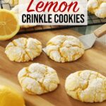 Four Lemon Crinkle Cookies sit on a wooden board, one actively being scooped up by a metal spatula while more lemon crinkle cookies cool on a rack in the background.