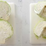 Cabbage cut on a white cutting board on a kitchen counter.