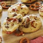 Pretzel chocolate chip cookies on a wooden cutting board.