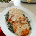 Sliced air fryer turkey on a white platter with fresh herbs.