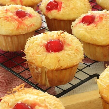 Piña colada muffins on a wire cooling rack in a kitchen.