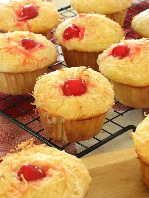 Piña colada muffins on a wire cooling rack in a kitchen.